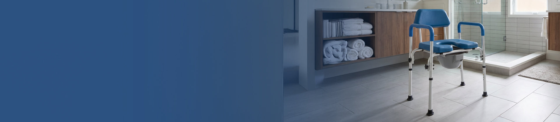 A blue shower chair with armrests and a cutout seat is placed in a modern bathroom next to a walk-in shower and shelves with neatly folded towels.