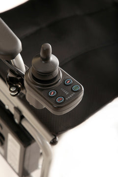 Close-up of the joystick control panel with multiple buttons and indicator lights, mounted on the armrest of the Journey Air Elite Lightweight Folding Power Chair with a black fabric seat.
