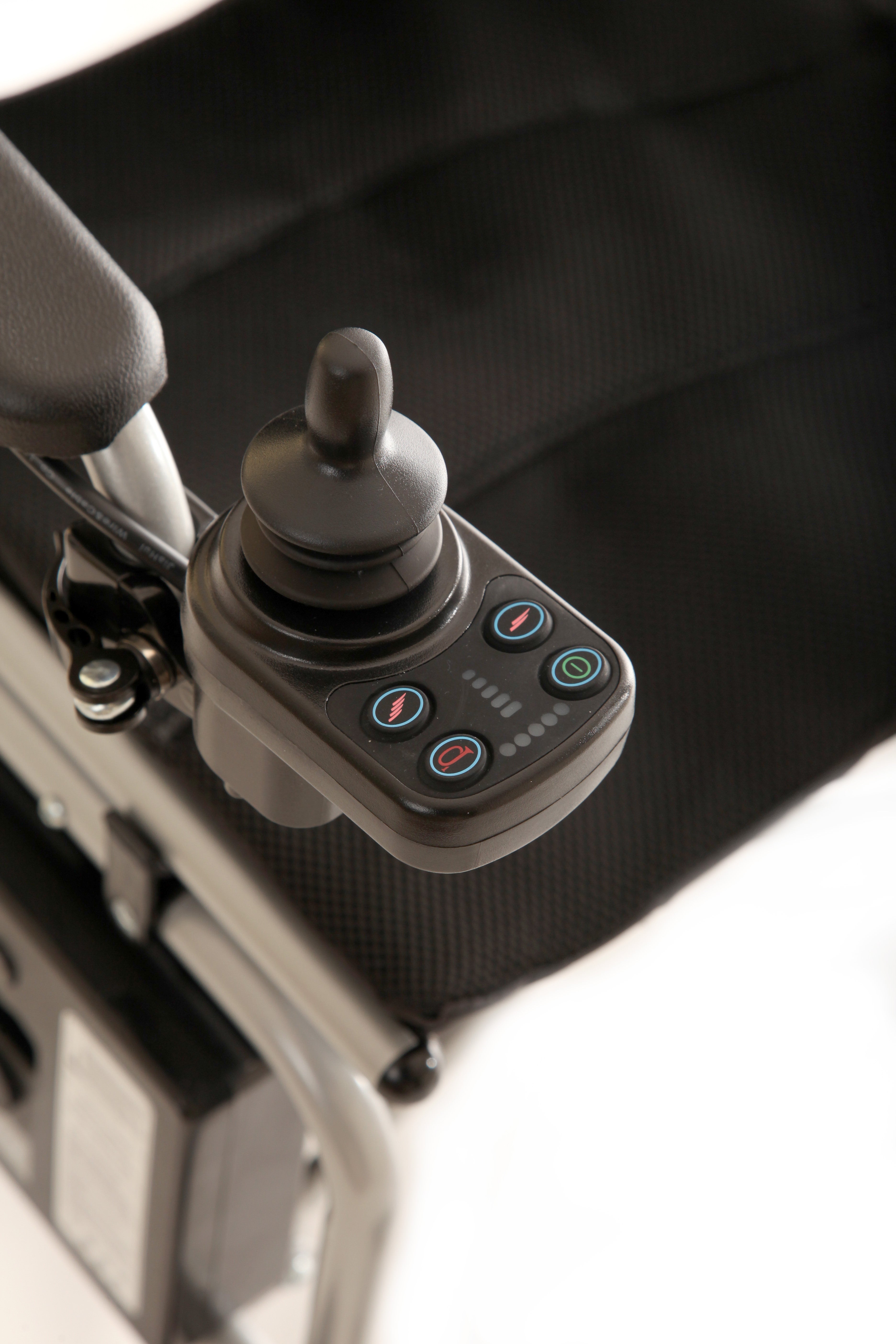 Close-up of the joystick control panel with multiple buttons and indicator lights, mounted on the armrest of the Journey Air Elite Lightweight Folding Power Chair with a black fabric seat.