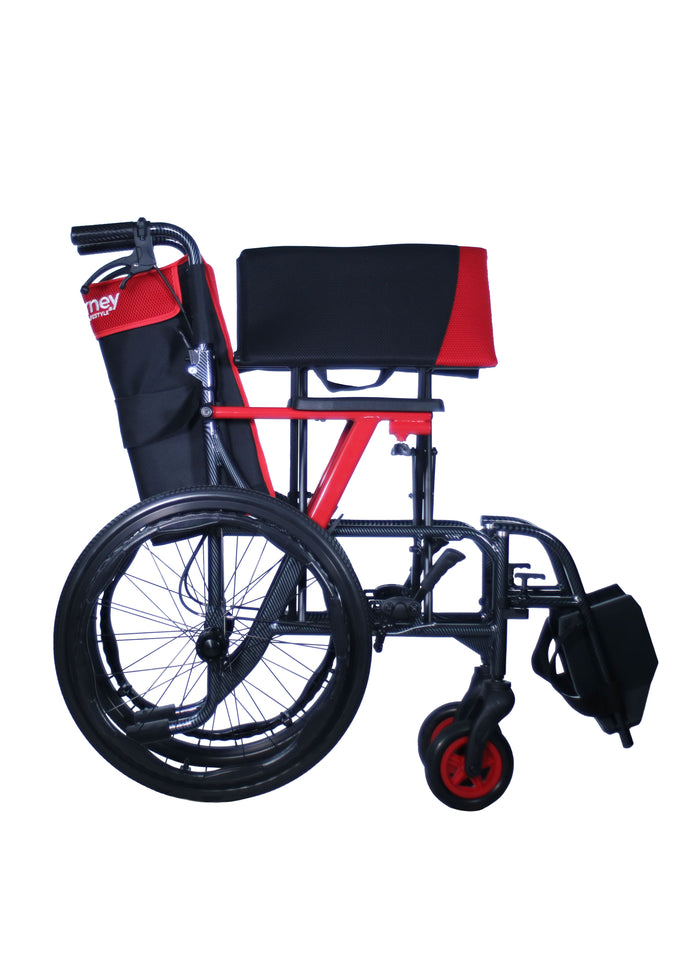 Side view of the Journey So Lite® C2 Ultra Lightweight Wheelchair featuring a red and black frame, large rear wheels, smaller front wheels, and a black seat and backrest. Includes a side storage pouch—perfect for travel.