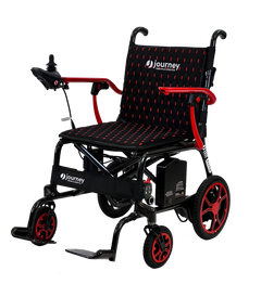 The Journey Air Elite Lightweight Folding Power Chair is a black and red compact wheelchair with joystick controls, cushioned seat and backrest, large rear wheels, small front wheels, footrests, and visible Journey branding.