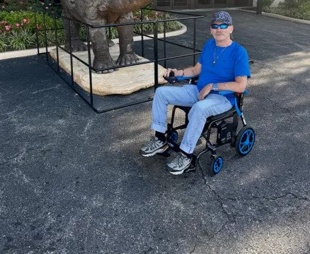 Person using a a Journey power chair on a paved surface with a large statue in the background