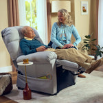 An older man relaxes in a Perfect Sleep Chair & Lift Chair, holding a remote with a drink on a side table. A smiling woman stands nearby, gently touching his arm as they chat in their comfortable living room.