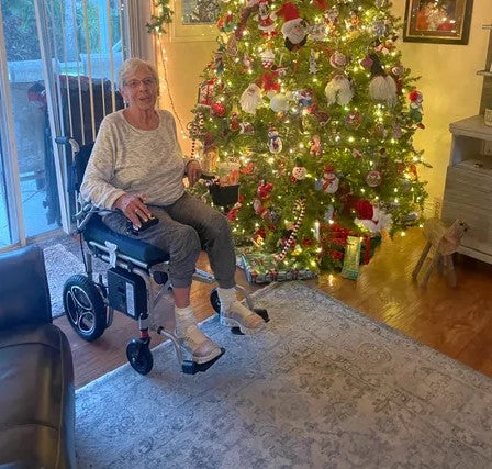 Woman in a Journey Power Chair sitting in front of a decorated Christmas tree.