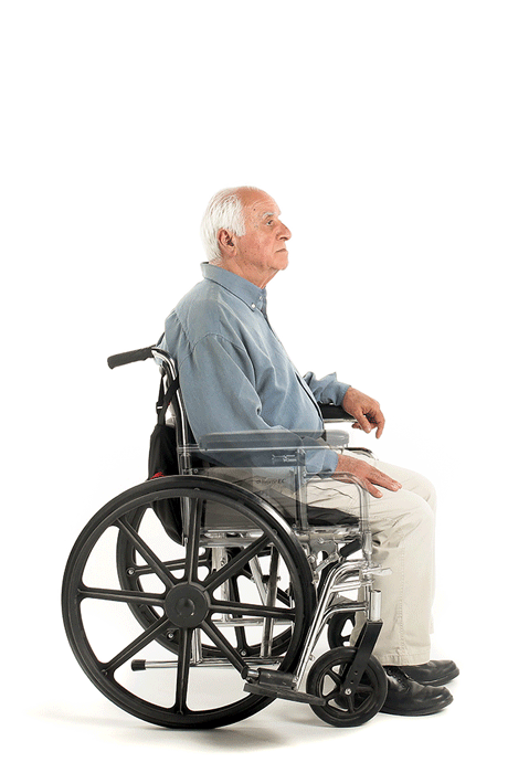 An older man with white hair, wearing a blue shirt and beige pants, sits in a wheelchair facing left on a white background, using the SitNStand Lift Assist Compact for Wheelchairs.