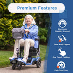 An older woman smiles while riding a Journey So Lite Folding Power Scooter on a sidewalk. Beside her, features are listed: electronic stability control, rear anti-tippers, one-touch folding, and flat-free tires.