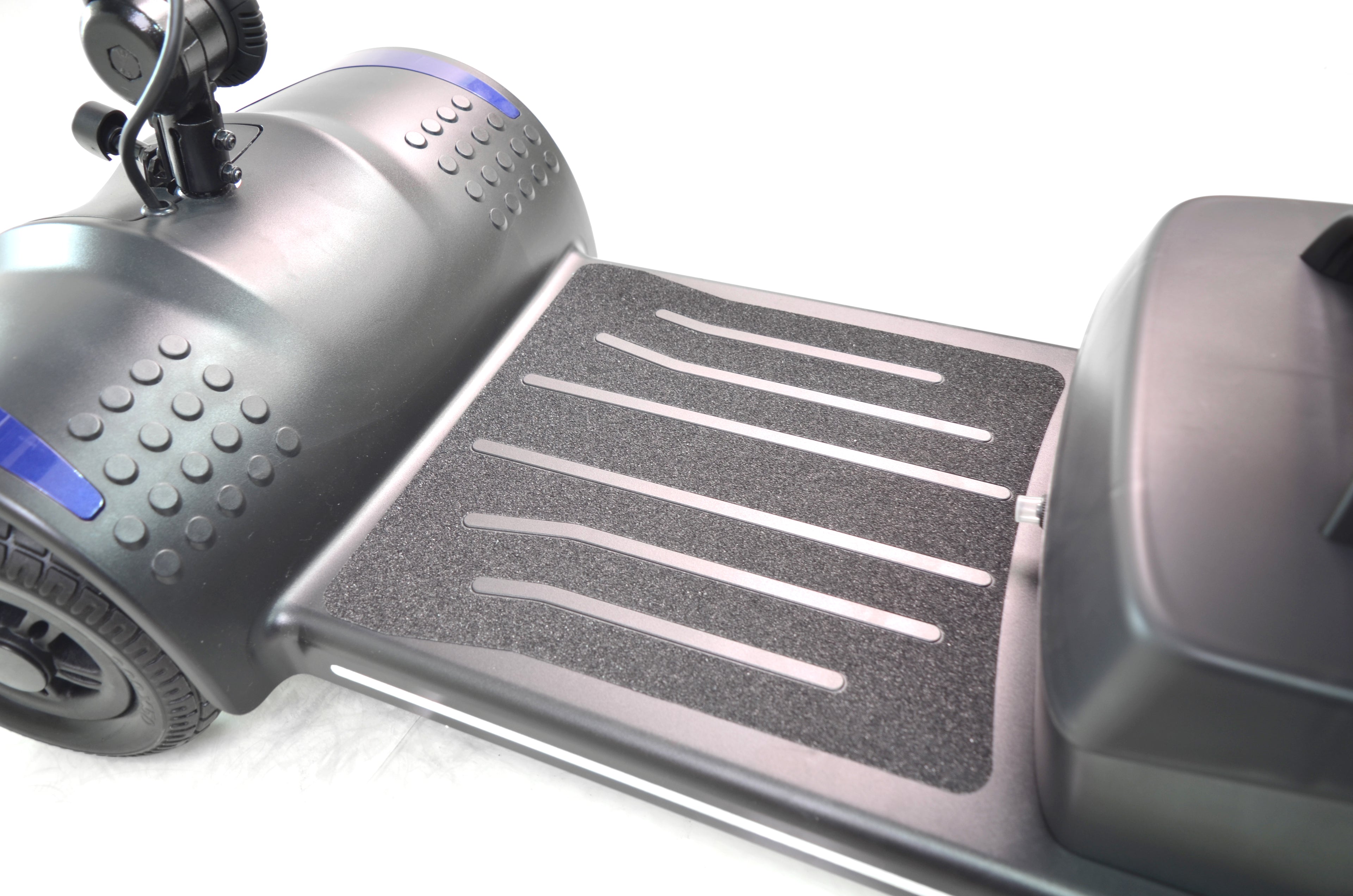 Close-up of the foot platform area of the Journey Adventure Scooter, featuring textured grip strips and part of the wheel and body in black, set against a white background.