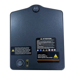A black rectangular lithium battery pack, like the Journey Air Elite Power Chair Battery Replacement 10Ah, features a power switch, indicator light, and various labels—including voltage and capacity details—on its surface.