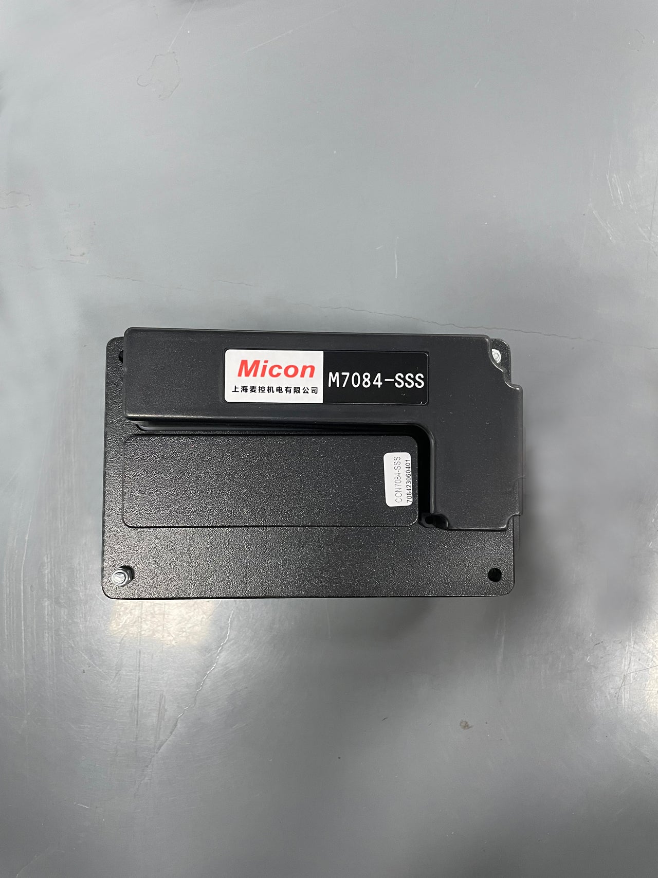 A black rectangular electronic module labeled Micon M7084-SSS with Chinese characters, shown on a gray surface—this is the Journey Air Elite - Replacement Main Controller, used for replacing or upgrading Journey Air Elite main controllers.