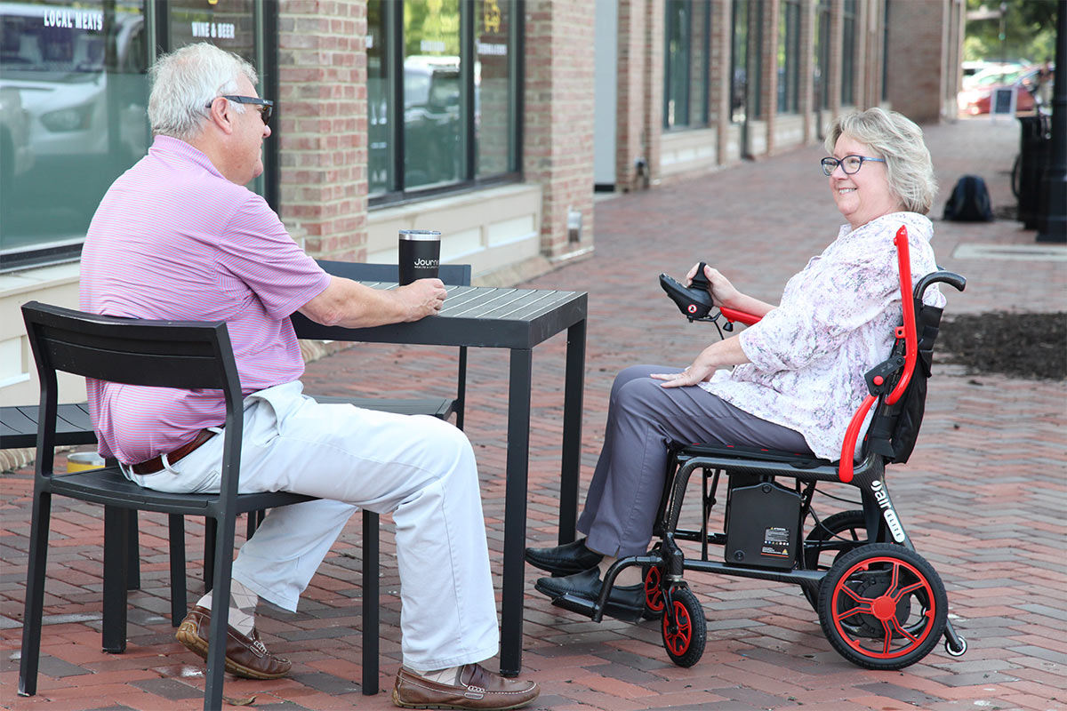 Image of a man in a chair and a woman in an Air Elite sitting at an outdoor table