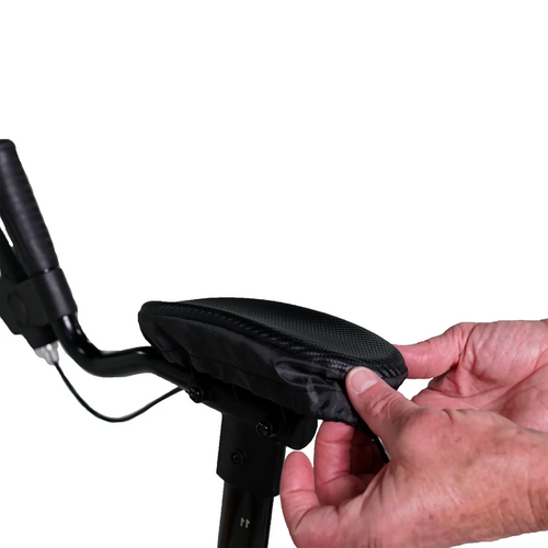 A person fits the UPWalker® Lite - Universal Arm Rest Pad, in black, onto an armrest, using one hand to hold the pad and the other to smooth it, against a white background.