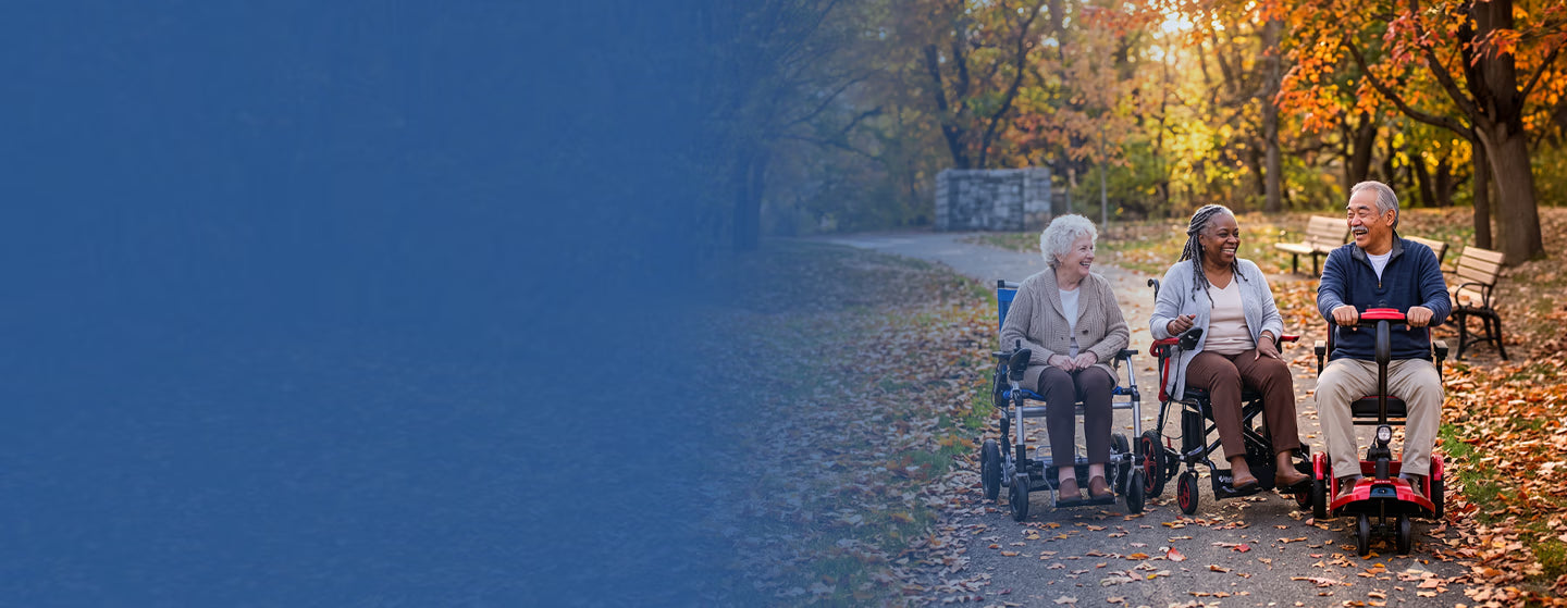 Three elderly people in Journey Power Wheelchairs and a So Lite motorized scooter sit on a leaf-covered path in an autumn park with colorful trees.