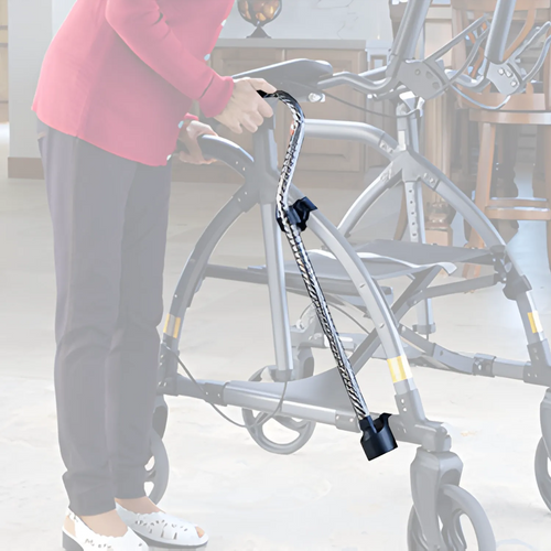 A person indoors holds a walker with a cane securely attached using the UPWalker® Cane/Umbrella Holder, keeping the cane suspended along the side of the walker for easy access.