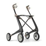 The byACRE Carbon Ultralight Rollator is a modern mobility aid featuring four large wheels, ergonomic handles, and a sleek black and tan minimalist frame for effortless movement.