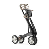 The byACRE Carbon Ultralight Rollator, shown standing upright on a white background, features a modern four-wheeled design with a sleek black frame, beige handle, and white-spoked wheels.