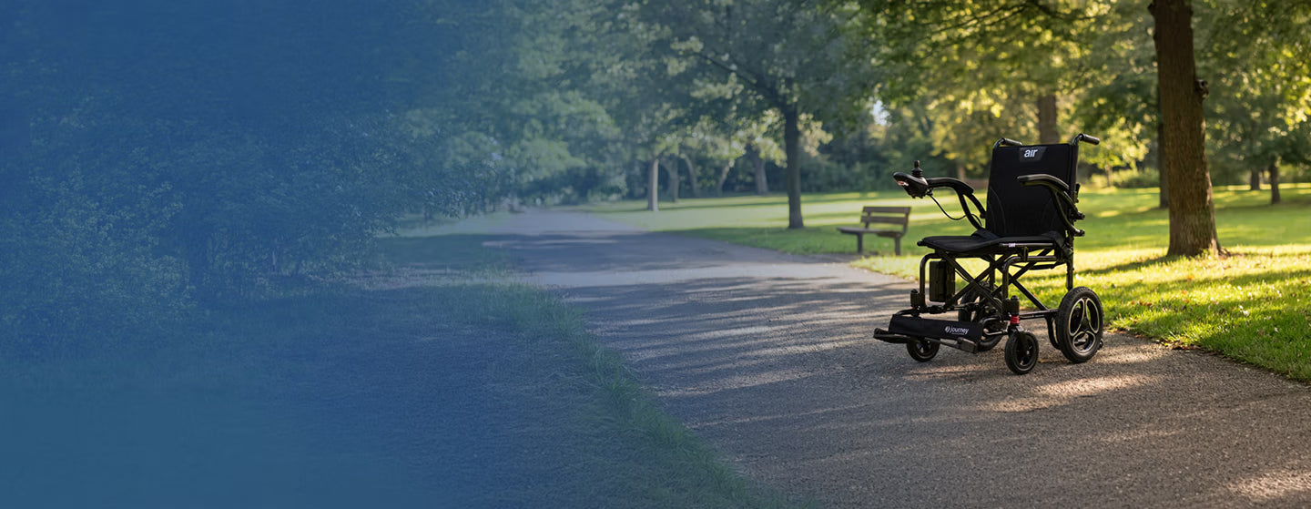Black Journey Air Series electric wheelchair on a paved path with greenery in the background