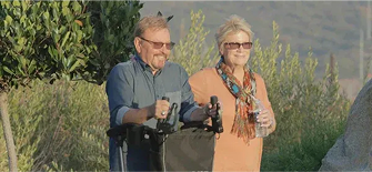 Two people riding segways in a scenic outdoor setting with trees and open space.