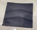 A black Journey Air Elite Power Chair Replacement Seat Cushion with textured surface and two raised, curved seams lies flat on a shiny, light-colored tiled floor.