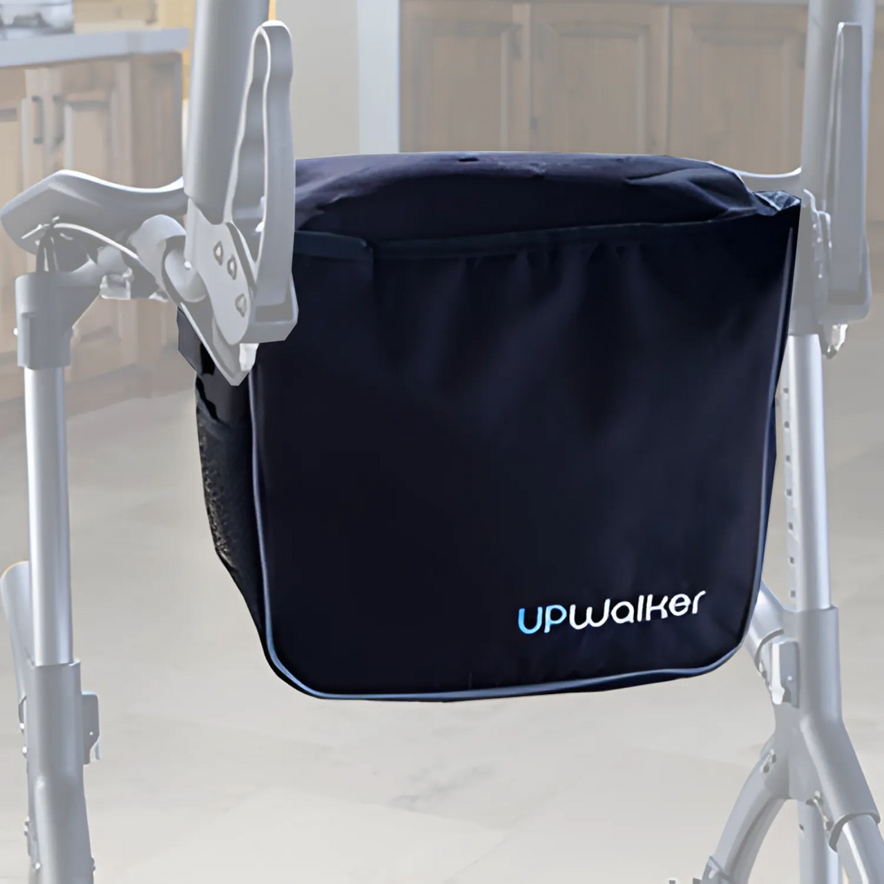 A close-up of the UPWalker® Luxury Personal Bag, made from durable fabric and attached to a walker handle. The zippered top and logo are visible, set against a blurred kitchen background.