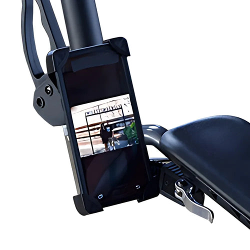 A close-up of a UPWalker® Smartphone Holder attached to exercise bike handlebars, securing a smartphone that displays an outdoor video. The bike seat and adjustment lever are visible, allowing for convenient handsfree use.