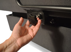 A hand adjusts a large black knob on the UPbed® Standard 4-in-1 Motorized Lift Bed’s metal rod, set against a textured dark gray surface, reminiscent of mechanisms in adjustable beds or memory foam mattress setups.