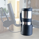 A stainless steel travel mug sits in a Journey UPWalker Cup & Beverage Holder attached to the handlebars of a mobility aid in a bright kitchen setting.