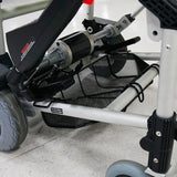 Close-up of the Journey Zinger Power Chair Basket – Portable & Strong, attached under the Zinger Power Chair’s sturdy metal frame and between its wheels, ideal for carrying mobility scooter accessories. The chair sits on a white tiled floor.