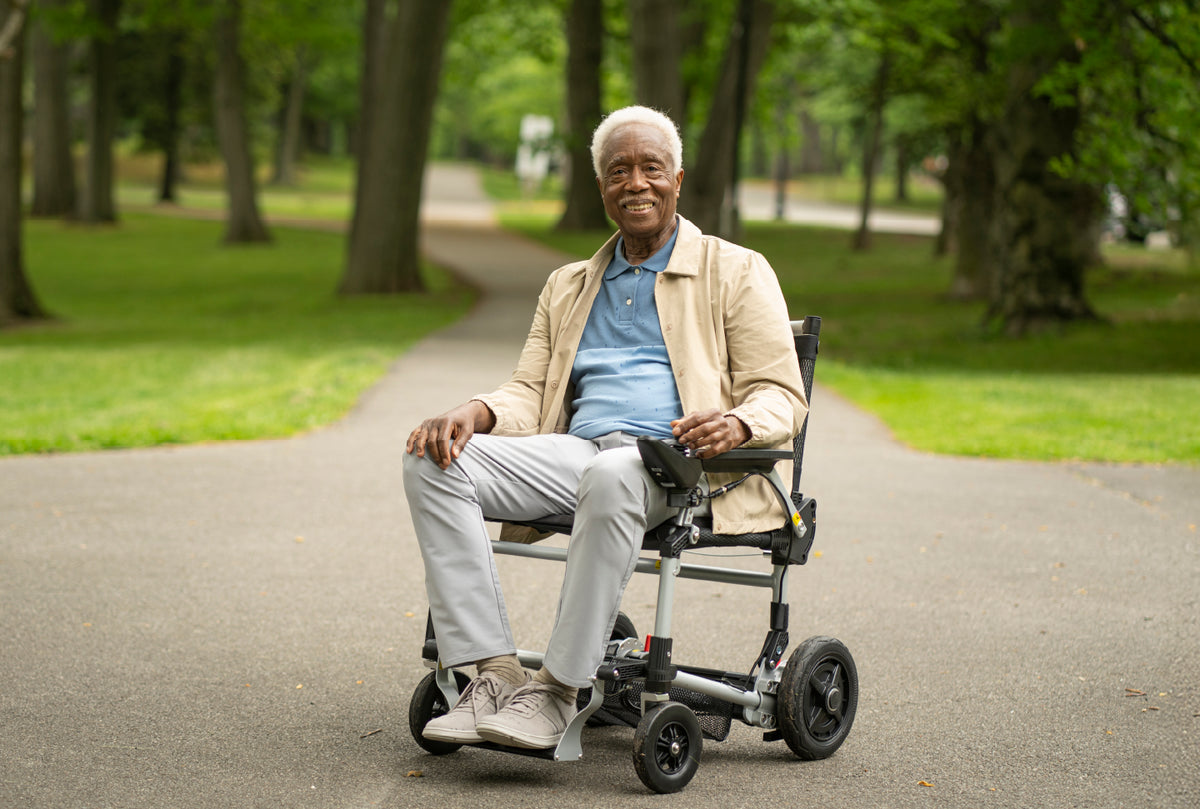 Man in a journey power wheelchair sitting on a path in a park