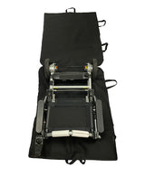A folded electric wheelchair sits on an open Journey Zinger & Zoomer Power Chair Travel Bag, showing its wheels, seat, and control panel. The black bag has multiple handles along the edges for easy carrying.
