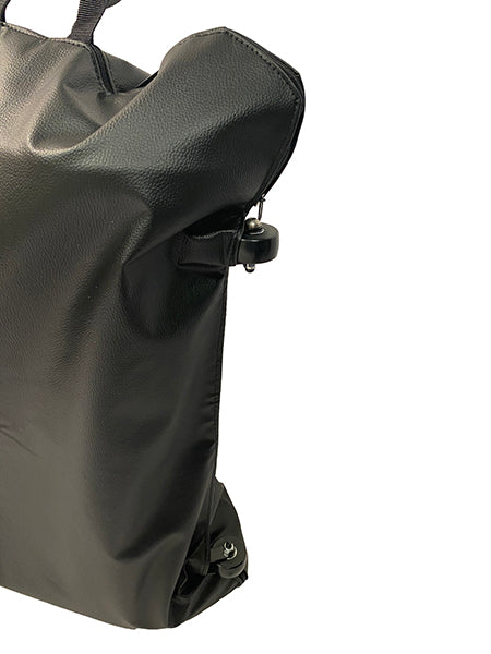 A close-up of a black, textured leather Journey Zinger & Zoomer Power Chair Travel Bag with zipper and buckle details, photographed against a white background. Only part of this stylish mobility power chair accessory is visible.
