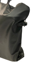 A close-up of a black, textured leather Journey Zinger & Zoomer Power Chair Travel Bag with zipper and buckle details, photographed against a white background. Only part of this stylish mobility power chair accessory is visible.