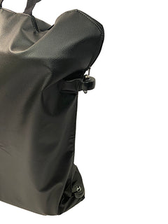 A close-up of a black, textured leather Journey Zinger & Zoomer Power Chair Travel Bag with zipper and buckle details, photographed against a white background. Only part of this stylish mobility power chair accessory is visible.